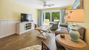 Een woonkamer met een televisie, bank en een tafel met een lamp.