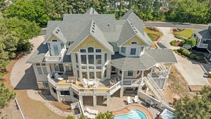 A large, multi-story house with a swimming pool, multiple decks, and a well-maintained lawn. - Mi Casa Bella: Private pool, hot tub, dog friendly, golf discounts & gated c (Corolla)