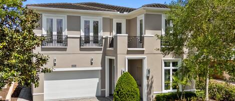 A two-story house with a garage, a balcony, and a well-maintained lawn.