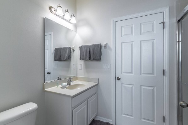 A bathroom with a white vanity, a mirror, and a door. - 4BR End Unit | Private Pool & Resort Perks | Near Disney | Exclusive Extended Stay Discounts (Kissimmee)