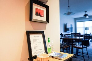 A framed welcome sign, a hand sanitizer bottle, and a small bowl on a table in a hotel room. - Stunning Condo w/Channel Views in the highly (Grand Haven)