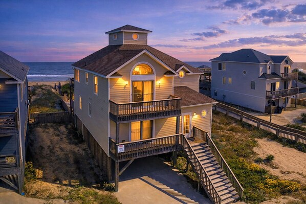 Ein Strandhaus mit Balkon, einer Treppe zum Eingang und Blick auf das Meer.