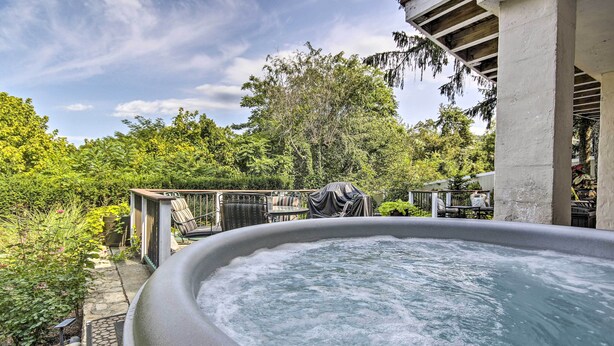 An outdoor hot tub surrounded by lush greenery and a covered patio area.