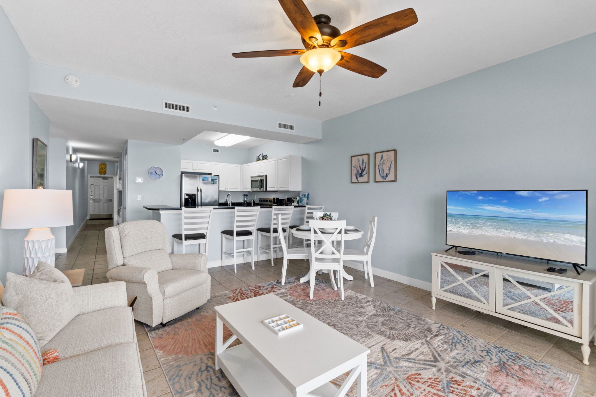 A modern living room with a ceiling fan, a TV, and a dining area with chairs and a table.