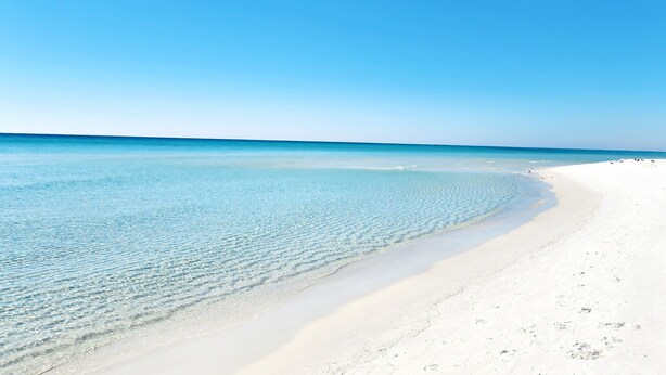 Una playa con aguas azul turquesa y arena blanca.