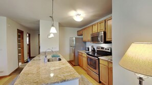 A kitchen with granite countertops, stainless steel appliances, wooden cabinets, and a ceiling fan. - Cozy 2b/2b condo, great amenities, close to Lake Dillon. (Dillon)