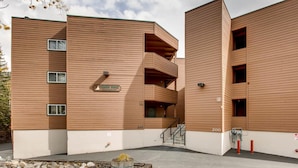 Un edificio moderno con facciata in legno, diversi balconi e una targa che indica che si tratta di un condominio.