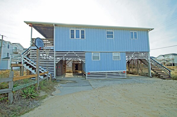 A two-story building with a blue exterior, a wooden staircase, and a metal gate.