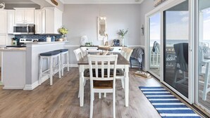 A spacious kitchen with white cabinets, a central island, and a dining area with a large table and chairs. - Sweet Carolina - Perfect Surfside Oceanfront Location! (Surfside Beach)