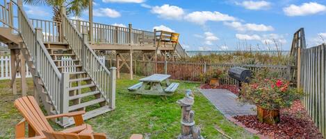 Un jardin avec une terrasse en bois, une statue en pierre et un barbecue.