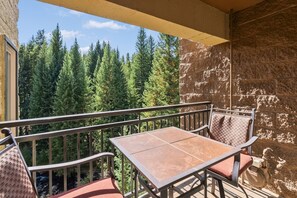 A balcony with a table and chairs, overlooking a forest. - Walking distance to lifts/town! Underground parking! (Breckenridge)