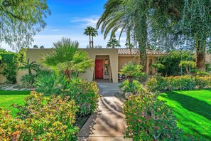 A well-maintained garden with a pathway leading to a building with a red door and the number 805. - Paseo El Mirador - 3 Bed 2 Bath Home (Palm Springs)