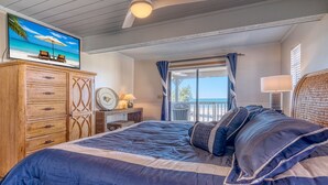 Un dormitorio con una cama grande, un aparador de madera y un cuadro de una playa.