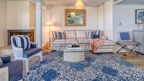 Una sala de estar con un sofá modular, una mesa de centro de vidrio y un tapete estampado.