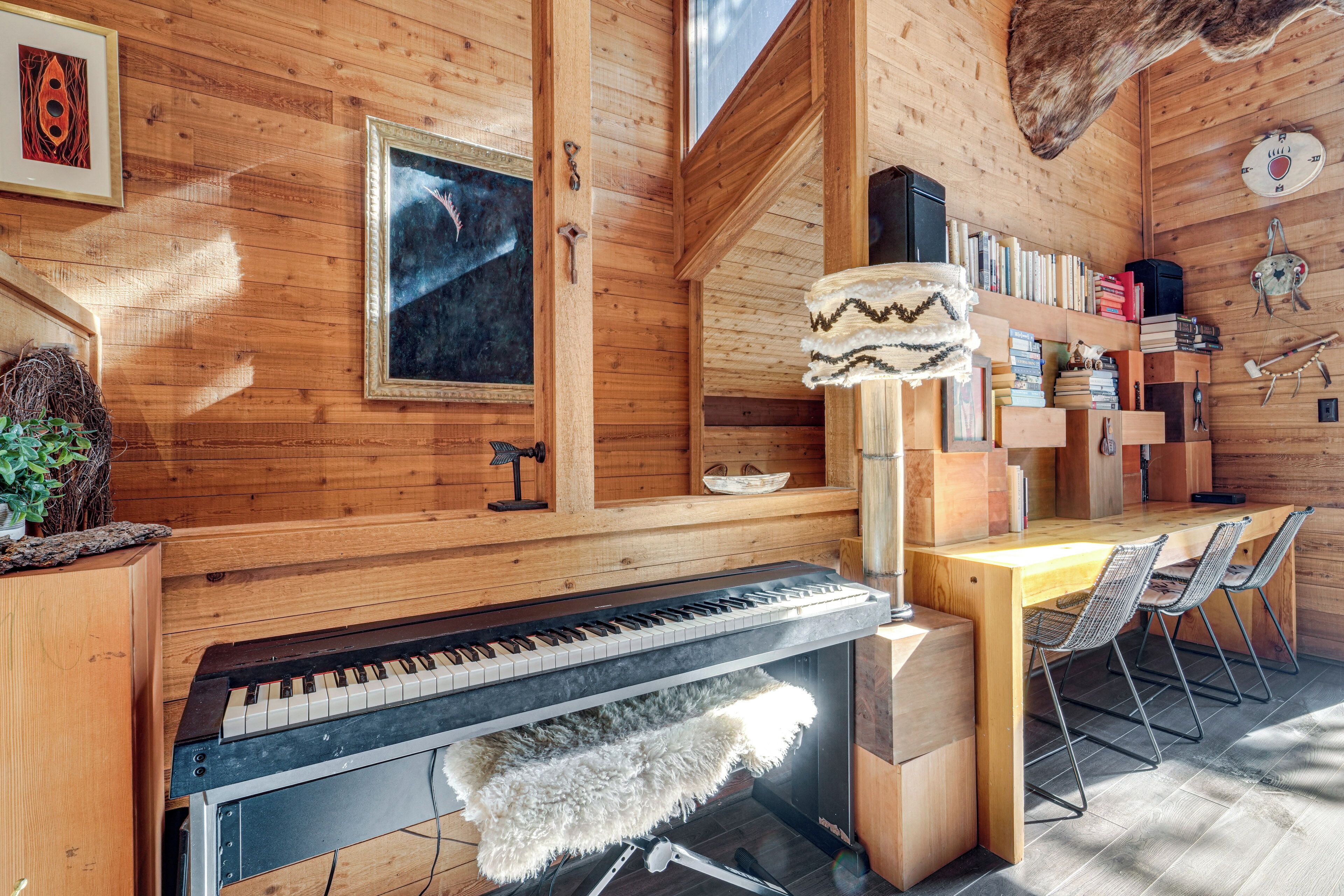 Un intérieur en bois avec un piano, des étagères et un coin repas.