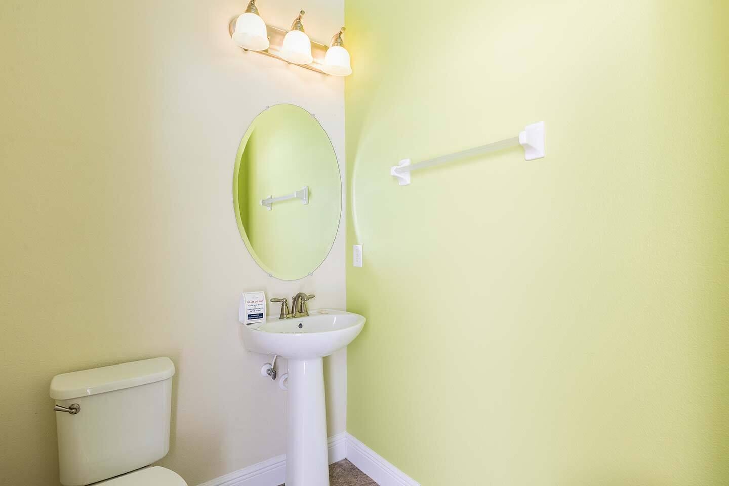Et badeværelse med toilet, vask, spejl og håndklædestang.