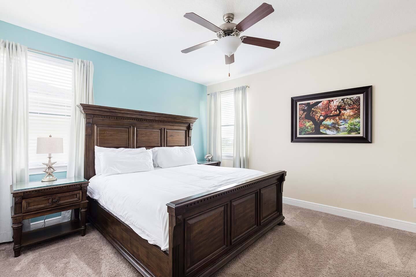 A bedroom with a wooden bed, a nightstand, a lamp, and a ceiling fan.