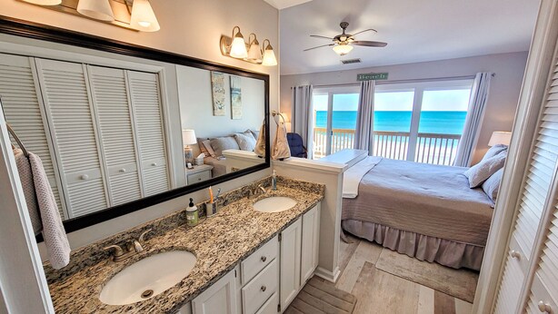 A bathroom with a large mirror, two sinks, and a ceiling fan. - 910-B Turtle Cove: Beachfront Fun & Pool Access! (Surf City)