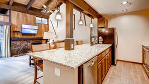 Una cocina con encimeras de granito, armarios de madera, horno empotrado y refrigerador.