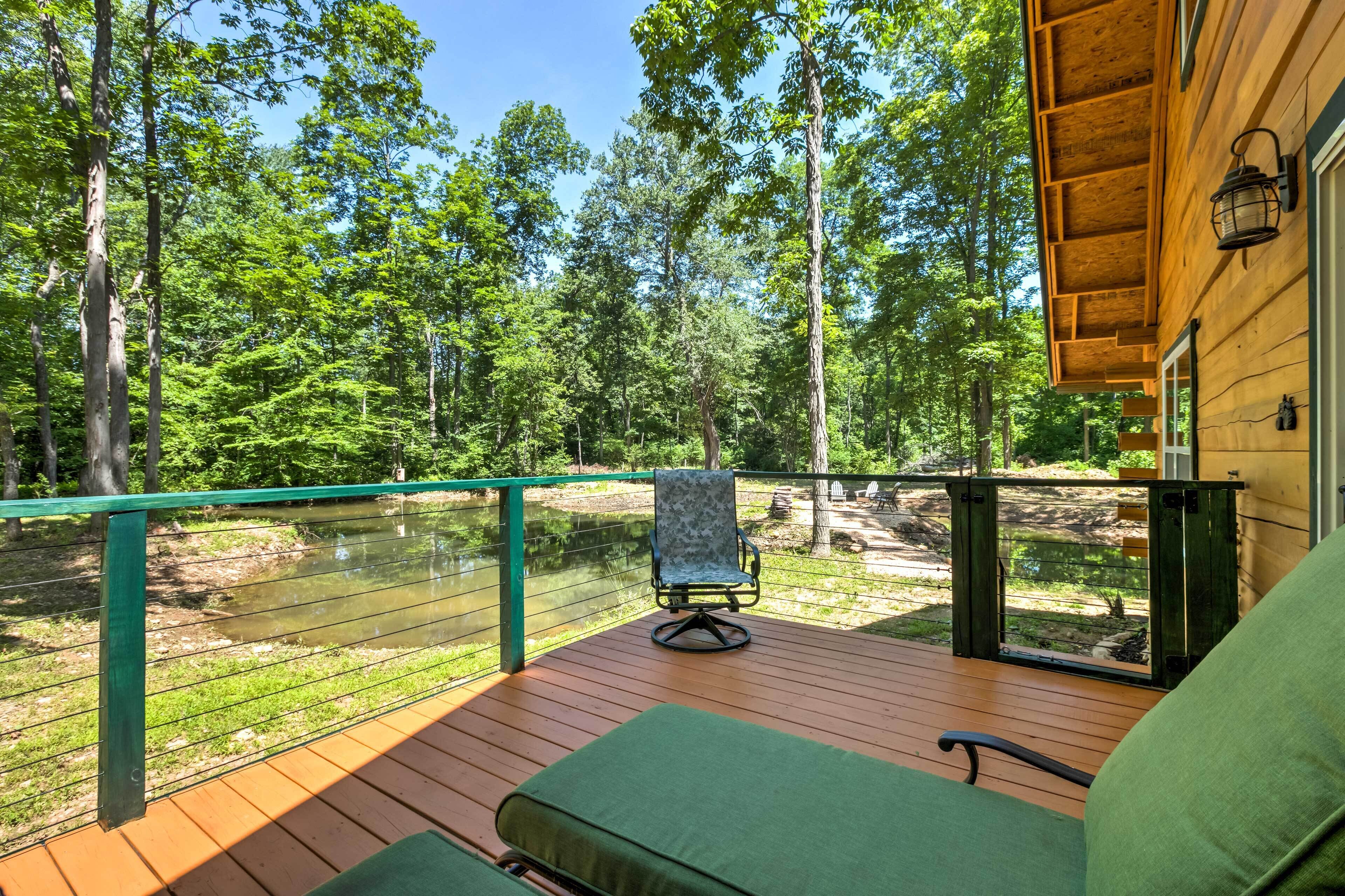 A wooden deck with a green cushioned chair and a view of a forested area.