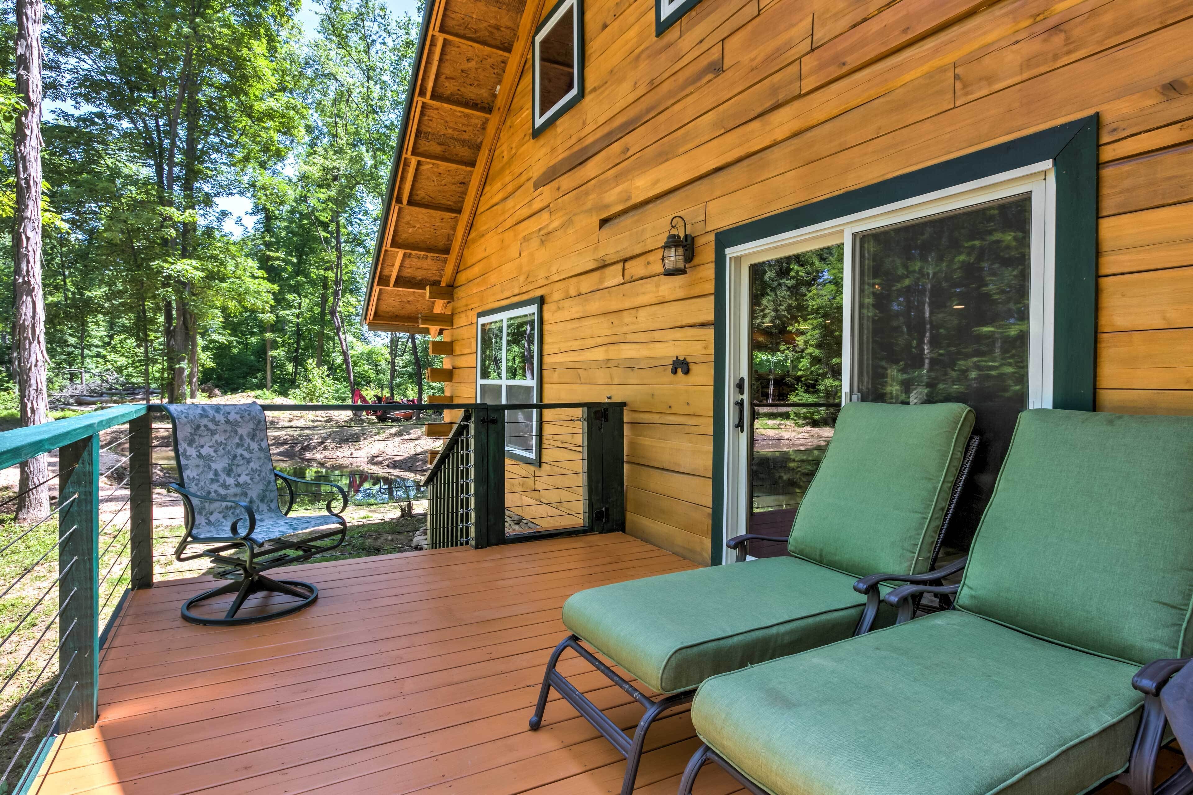 A wooden deck with two green cushioned chairs and a small table.