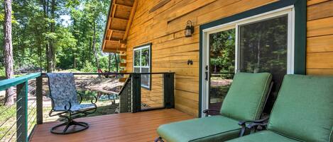 A wooden deck with two green cushioned chairs and a small table.