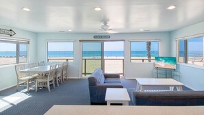 A beach house interior with a dining area, sofa, and TV. - A magnificent view awaits you as you enter...this upper unit is one-of-a-kind! (Newport Beach)