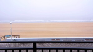 A wooden deck with a railing overlooking a beach. - Adorable, spacious 2-bedroom oceanfront condo with free WiFi and a fabulous ocean view located directly on the Boardwalk! (Ocean City)
