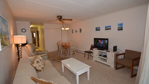 Una sala de estar con sofá, mesa de centro, mueble para la televisión y una zona de comedor con sillas y una mesa.
