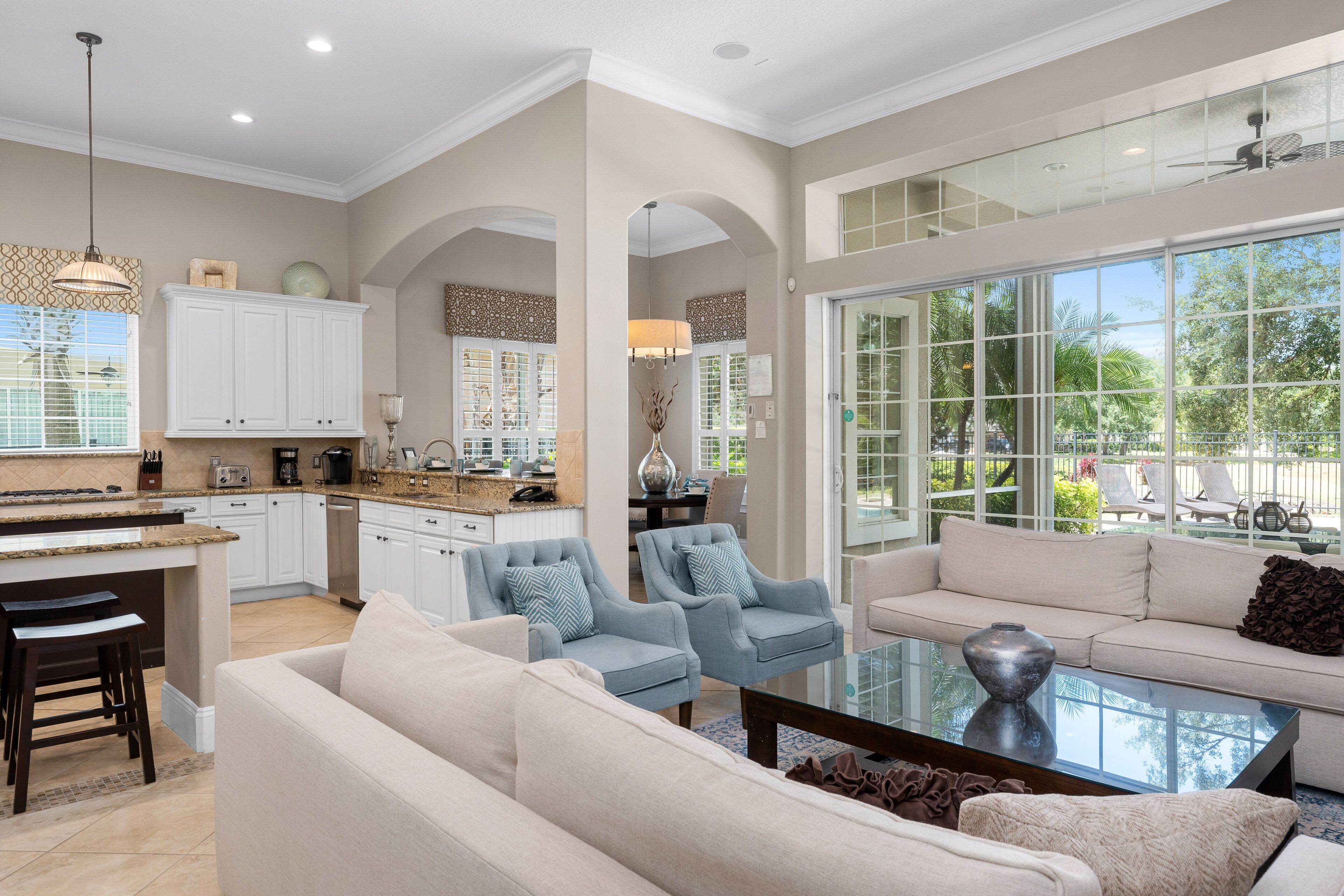 A spacious living area with a large window, a kitchen with white cabinets, and a dining area.