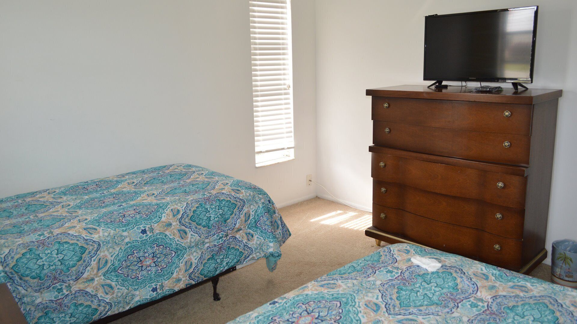 Une chambre avec deux lits, une commode et un téléviseur.
