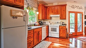 A kitchen with wooden cabinets, a refrigerator, a microwave, and an oven. - Cozy Scottsville Cottage w/ River Views & Gazebo! (Scottsville)