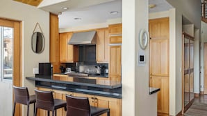 A modern kitchen with wooden cabinets, a black countertop, and three bar stools.