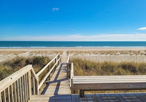 A wooden boardwalk leading to a beach with a bench in the foreground. - Schoonderwoerd: Timeless Charm, Ocean Breezes (Topsail Beach)