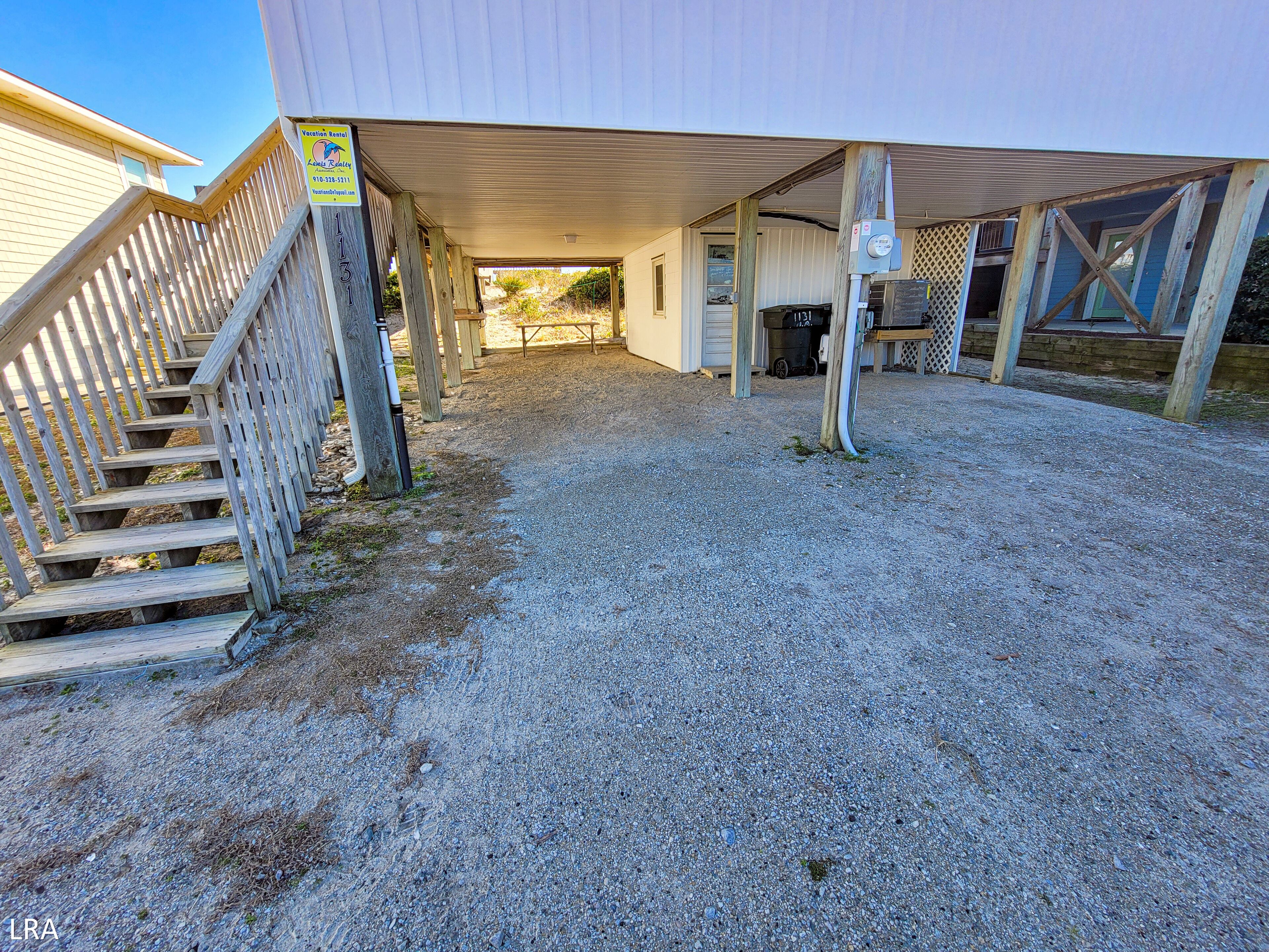 A covered outdoor area with a gravel path leading to a building entrance.