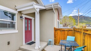 Una casa con puerta roja, un pequeño porche y valla de madera.