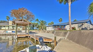 A boat docked at a marina with a wooden pier, a covered seating area, and a stone building in the background. - Private Dock, Views: Waterfront Rockport Home! (Rockport)