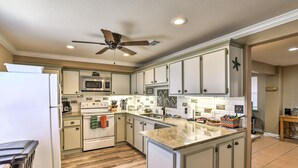 A kitchen with white cabinets, a microwave, an oven, a ceiling fan, and wooden flooring. - Private Dock, Views: Waterfront Rockport Home! (Rockport)