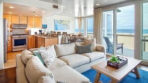Un vaste espace de vie comprenant un grand canapé, une table basse et une vue sur la plage.
