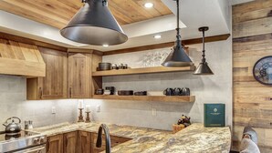 A modern kitchen with wooden cabinets, marble countertops, and pendant lighting. - Remodeled! Near Downtown Breckenridge! (Breckenridge)