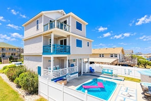 A two-story house with a balcony, a swimming pool, and a deck area.
