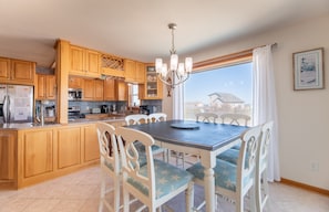 A kitchen with wooden cabinets, a stainless steel refrigerator, and a dining area with a table and chairs.