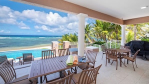 A covered outdoor dining area with a view of the ocean and beach.