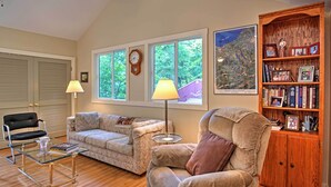 A living room with a sofa, armchair, and a wooden bookshelf. - Harbert Cottage w/ Fire Pit: Half Mile to Beach! (Harbert)