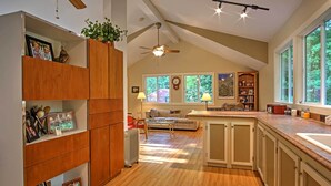 A spacious kitchen with wooden cabinets, a ceiling fan, and large windows offering a view of the outdoors. - Harbert Cottage w/ Fire Pit: Half Mile to Beach! (Harbert)