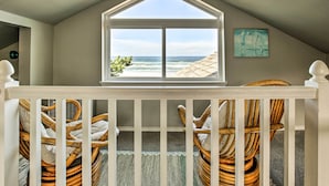 A balcony with wicker chairs, a view of the ocean, and a framed artwork on the wall. - Oceanfront Escape w/ Pacific Views: Surf & Explore (Arch Cape)