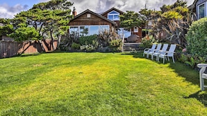 A backyard with a wooden house, a lawn, and a barbecue area. - Oceanfront Escape w/ Pacific Views: Surf & Explore (Arch Cape)