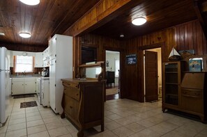 A kitchen with wooden cabinets, a refrigerator, and a wooden dining table.