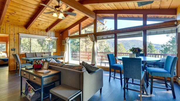 A wooden cabin interior with a dining area, sofa, and a ceiling fan. - Stunning Idyllwild Home w/ Private Hot Tub & Decks (Idyllwild)