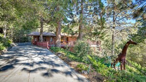 A pathway leading to a cabin surrounded by trees and a giraffe statue. - Stunning Idyllwild Home w/ Private Hot Tub & Decks (Idyllwild)